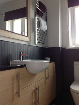 Bathroom with bath, toilet, electric shower and vanity unit with sink, heated towel rail.